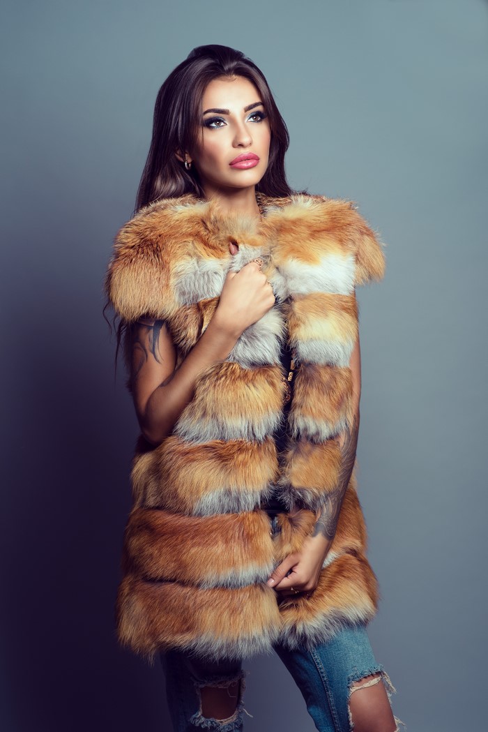 Woman in fur coat and ripped jeans