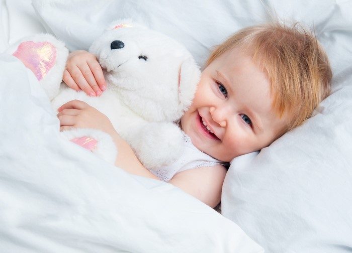 Infant smiling with a teddy bear