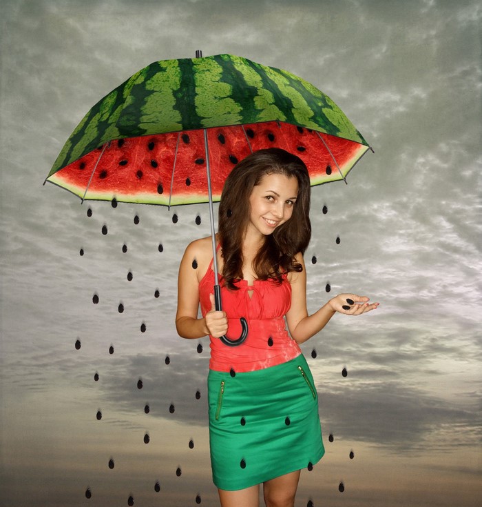 Woman holding a watermelon umbrella with watermelon seeds falling