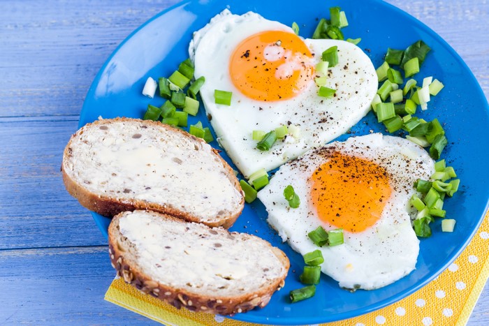 Two heart-shaped fried eggs with bread on a plate