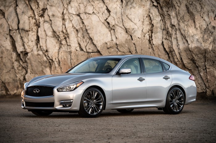 Silver Infiniti Q70 sedan parked in front of a rock face