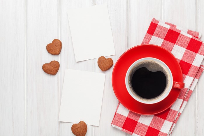 Coffee cup with heart cookies and blank cards on wood