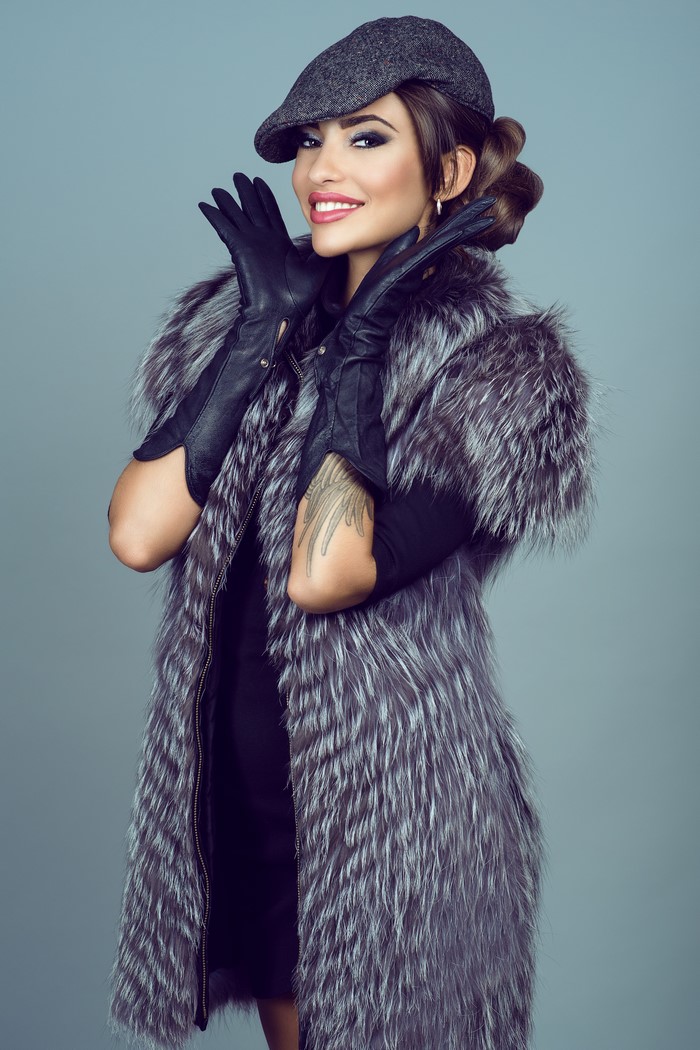 Woman in fur coat and cap wearing gloves