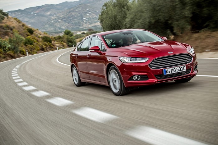 Red Ford Mondeo driving on a winding road