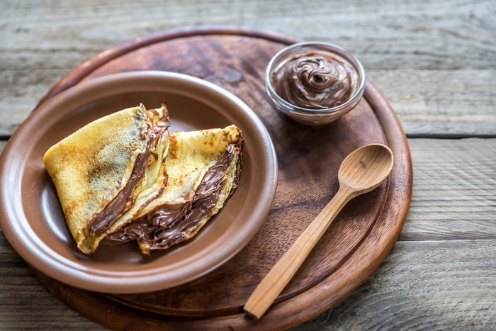Crepes with chocolate spread on a wooden board
