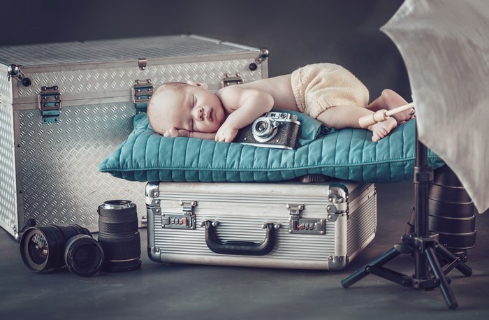 Baby sleeping on suitcases with camera equipment