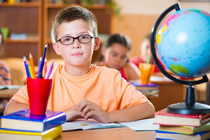 Boy with glasses and globe in classroom