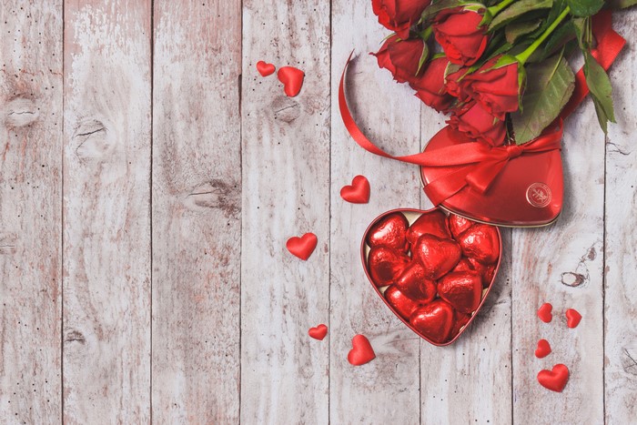 Valentine's Day roses and heart-shaped chocolates on wood planks