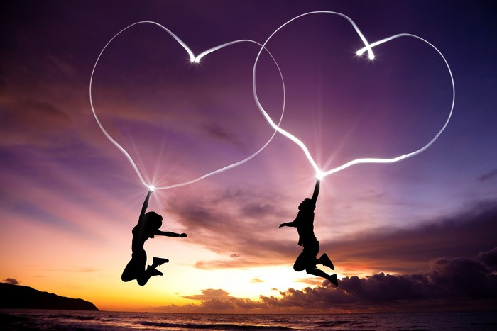 Two Silhouettes Drawing Hearts at Sunset