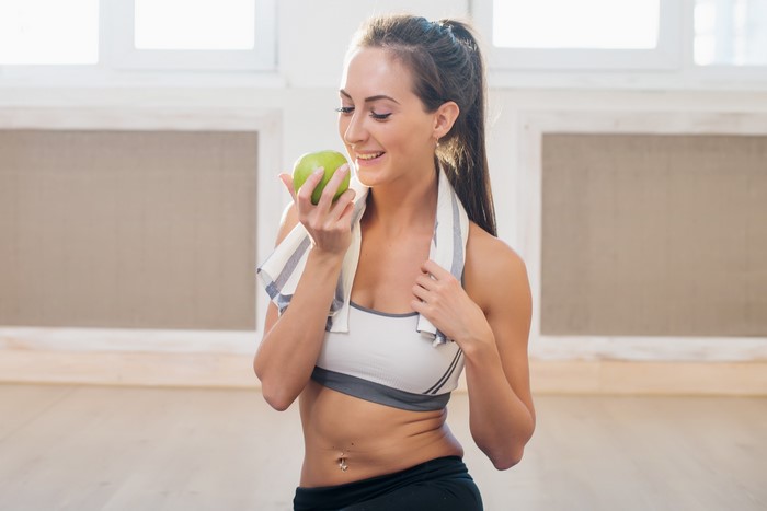 Woman in Sportswear Holding an Apple