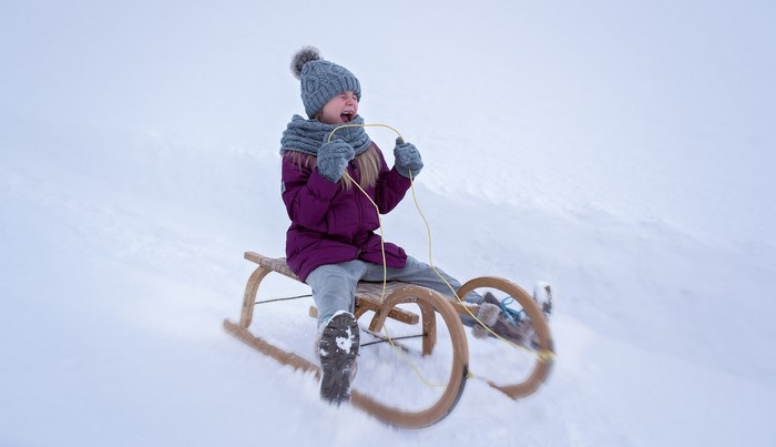 Girl screaming while sledding down a snowy hill