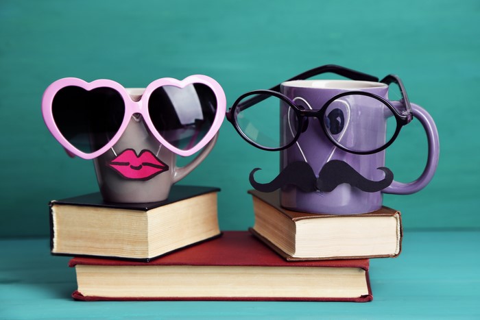 Mugs with heart sunglasses and mustache on books