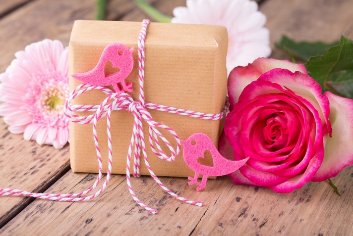Gift box with pink birds and flowers on wood