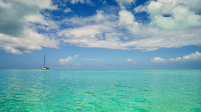 Catamaran sailing in turquoise waters under a cloudy sky