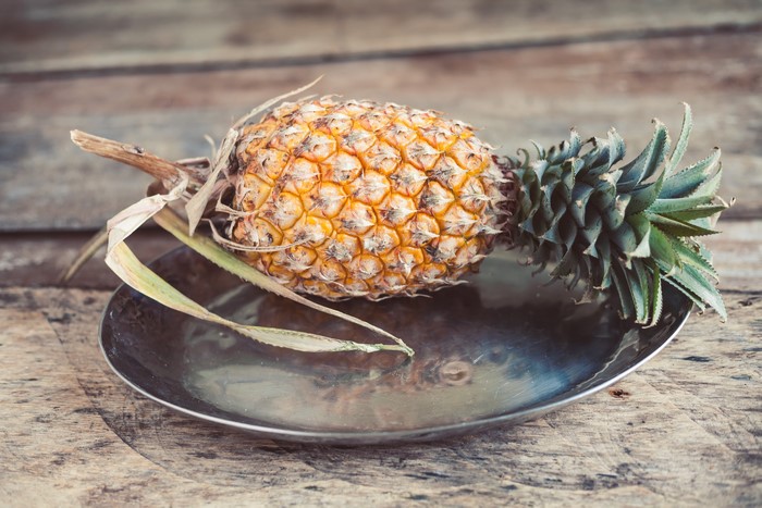 Pineapple on a plate on wood planks
