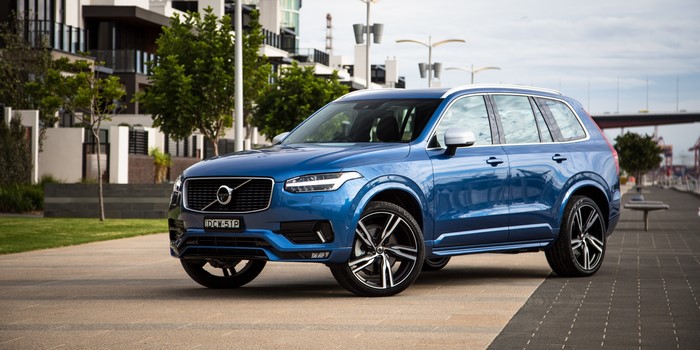 Blue Volvo XC90 parked by waterfront buildings
