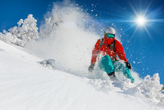 Man skiing down a snowy slope under the sun