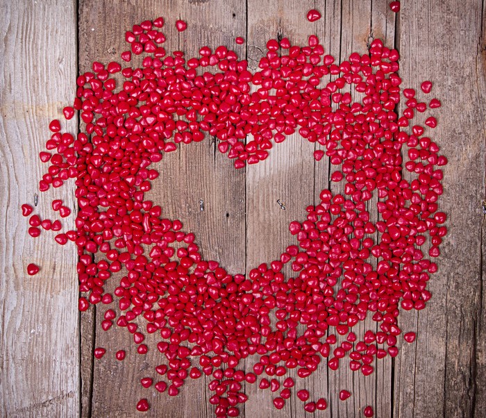 Red heart candies arranged on wooden planks