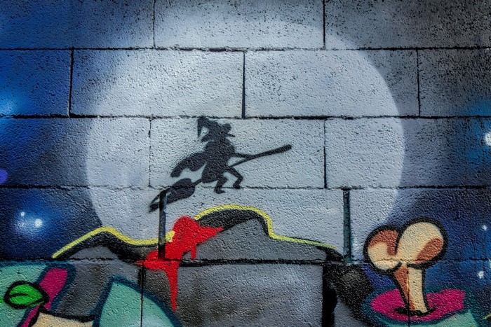 Graffiti of a witch on a broomstick in front of a moon