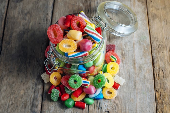 Jar of colorful assorted candies on wooden planks