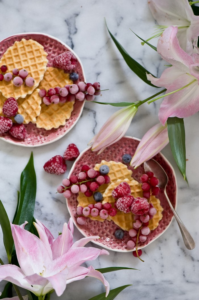 Waffles with berries and lilies on a marble table