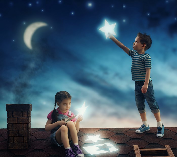 Children cutting and reaching for stars on a roof at night