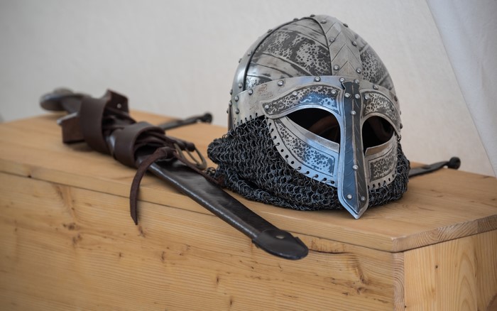 Viking helmet and sword on wooden surface