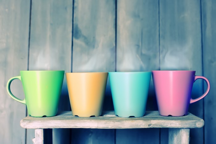 Four colorful mugs on a wooden shelf