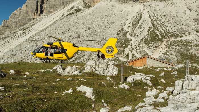Yellow helicopter lands near mountain hut