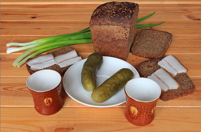 Bread, Cucumbers, Salo, Green Onions, and Mugs on Wood