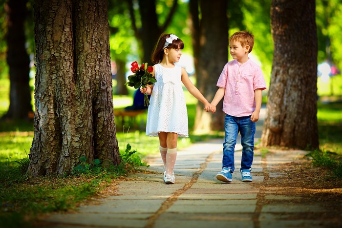 Children holding hands in a park with flowers