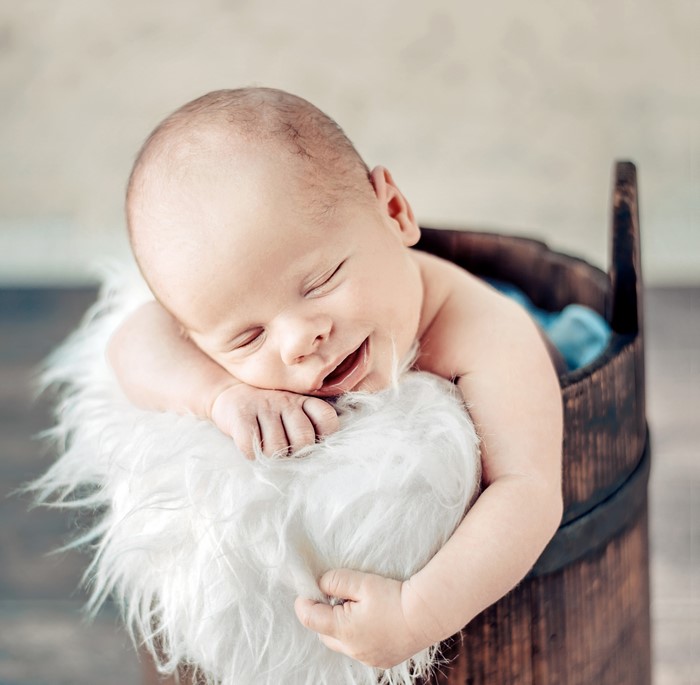 Newborn baby sleeping in a wooden bucket