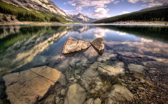 Rocky lake with mountains and forest reflection