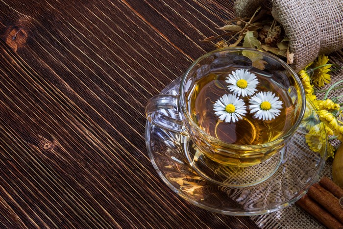 Cup of chamomile tea with flowers on wooden table