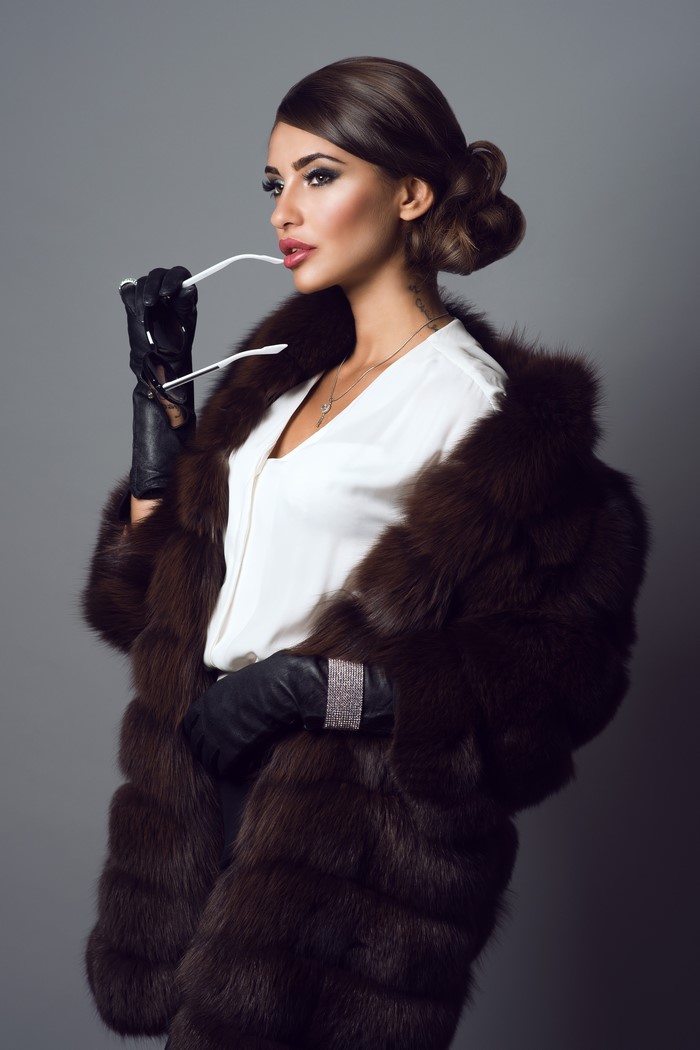 Woman in fur coat holding glasses