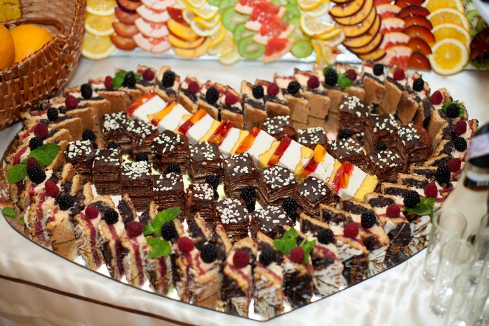 Heart-shaped platter of assorted mini cakes and fruit slices