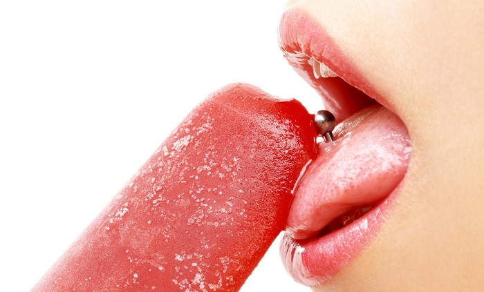 Woman's tongue with piercing licking popsicle
