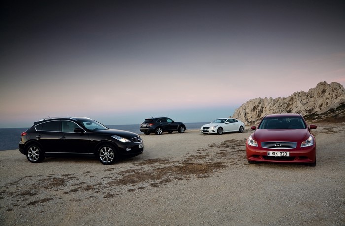 Four Infiniti cars parked on a rocky coast