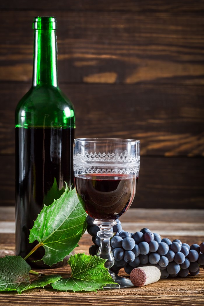 Bottle of red wine with glass and grapes