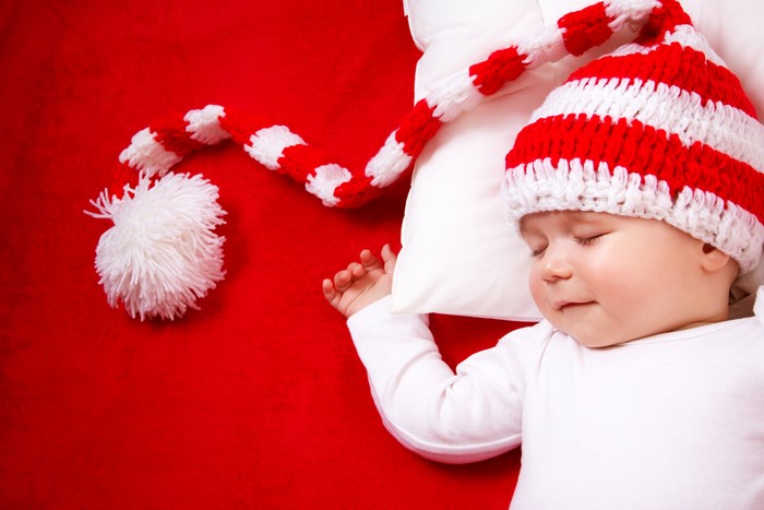 Baby sleeping in a red and white striped hat