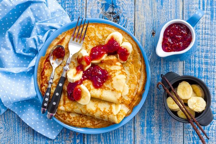 Pancakes with banana and jam on a blue plate