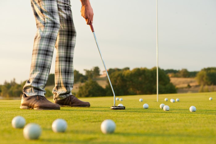 Golf player putting on a green field