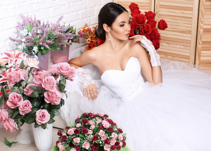 Bride in white dress with bouquets of roses
