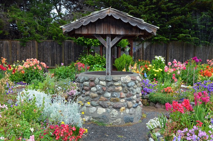 Stone water well in a colorful garden