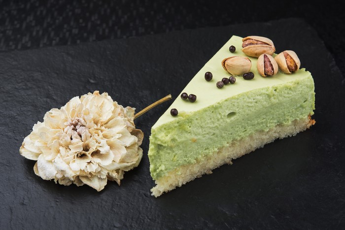 Slice of pistachio cake with pistachios and dried flower