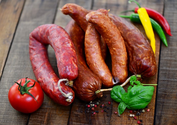 Sausages with tomatoes and chili peppers on wood