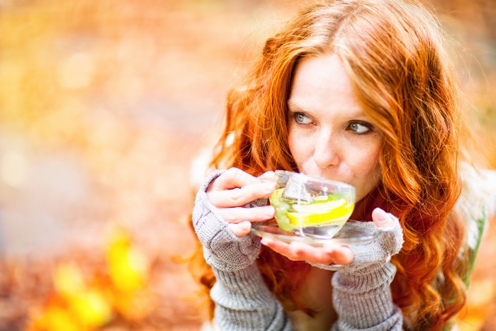 Redhead girl drinking tea in autumn