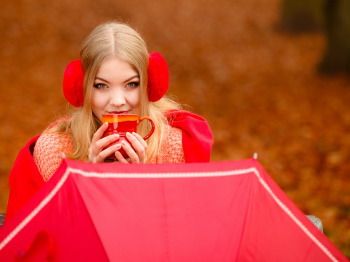 Blonde girl with cup and earmuffs in autumn