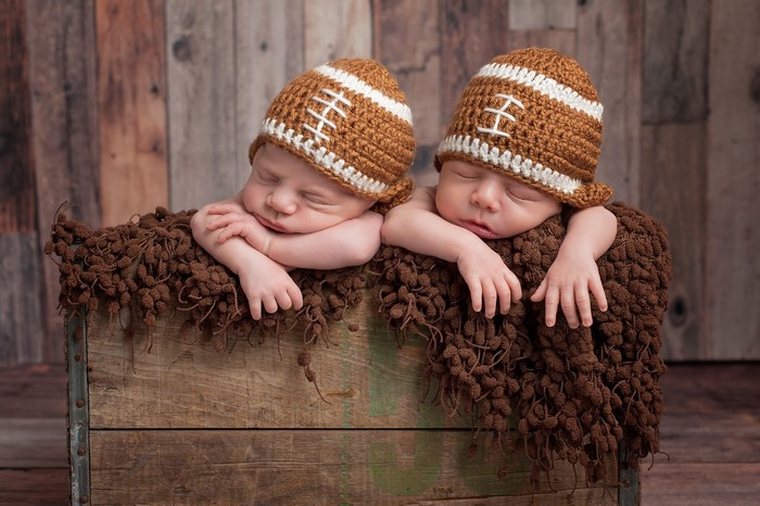 Two Newborn Babies Sleeping in Football Hats