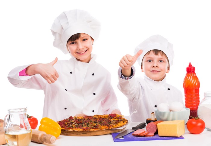Two young chefs with pizza and ingredients